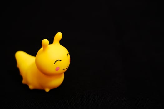 Happy Yellow Rubber Caterpillar on Dark Background photo