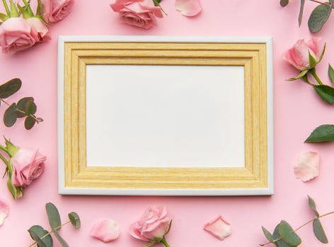 Wooden frame decorated with pink roses and eucalyptus leaves on pink background for valentine's day photo
