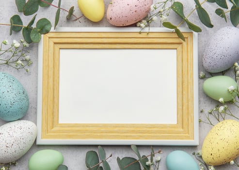 Easter wooden frame mockup surrounded by colorful eggs and eucalyptus leaves photo