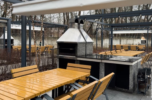 Trendy outdoor patio pergola shade structure, awning and patio roof, dining table, chairs, metal grill surrounded by landscaping photo
