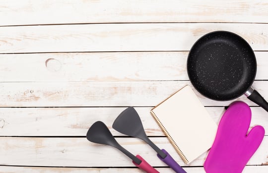 Cast iron pan and other kitchen utensils on wooden table, top view photo