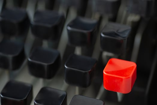 A red typing key stands out among black keys on a retro typewriter creating a striking visual contrast photo