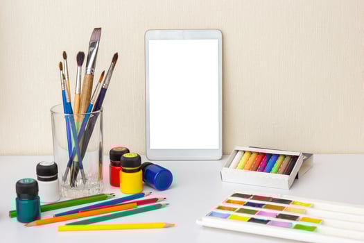 table with digital tablet on table with colorful drawing supplies photo