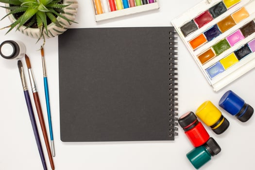 One black sketchbook on a white table with drawing supplies. photo
