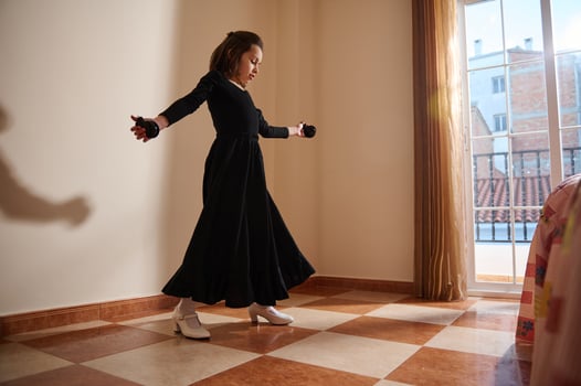 Young girl practicing dance moves in a sunny room with tiled flooring near a window photo