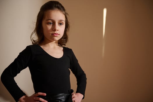 Confident young girl in black outfit poses gracefully in soft light photo