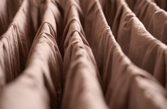 Abstract close up of brown textured fabric with pleats and folds in soft lighting. photo