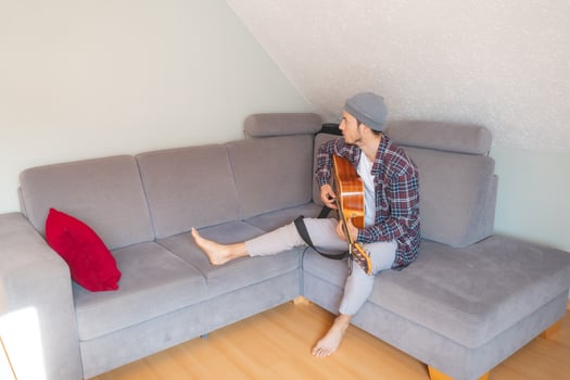Barefoot musician sits comfortably. Artistic focus captured in a cozy indoor scene photo