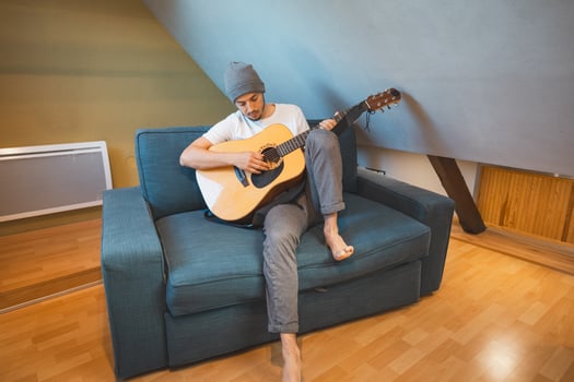 Musician 26 years old sits barefoot on a cozy. Artistic expression through solo acoustic performance photo