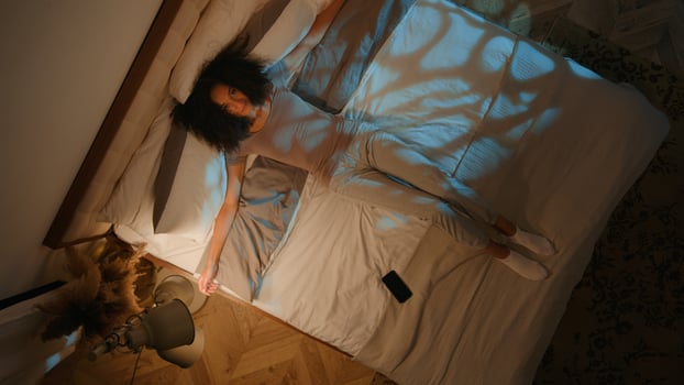 Top above view night bedroom African American woman using mobile phone in bed sending message online social media addiction tired girl falling on comfortable bed stretching arms relaxed smile at home photo