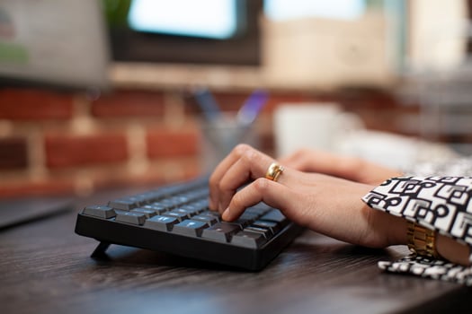 Closeup on the hands of a business person using keyboard on office desk. Female professional typing in data and updating company project plan on computer in modern workspace. photo