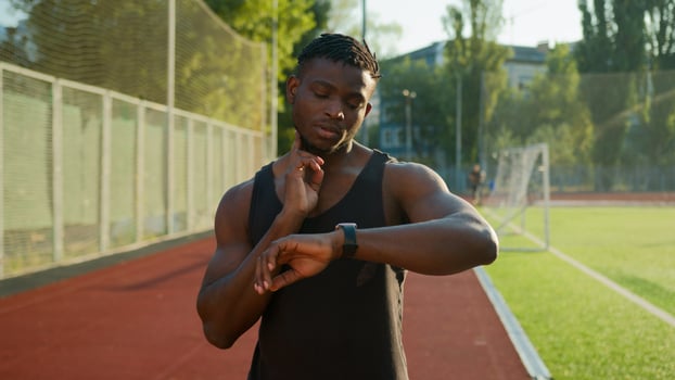 African American man runner jogger athlete muscular sportsman training outdoors athletic ethnic guy using smart band checking neck pulse heart rate result on smartwatch before running on sport stadium photo