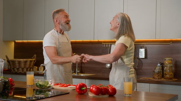 Romantic senior retired Caucasian family couple dancing waltz celebrate marriage anniversary cooking dinner old husband spin mid-aged wife in dance listen music at kitchen happy woman and man have fun photo