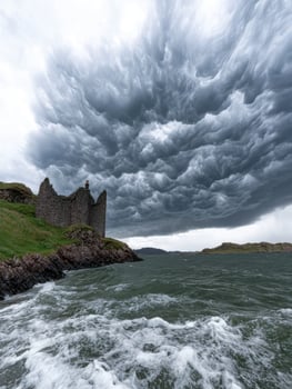 Dramatic storm clouds over a castle ruin on the coast of Scotland photo