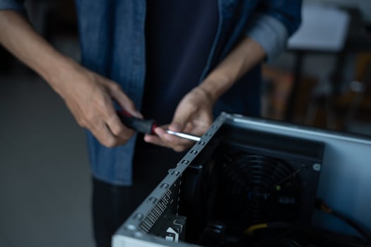 IT Engineer installing Hardware holding a screwdriver to a computer case photo