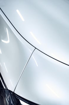 Sleek white car body with smooth curves and polished finish in a well-lit garage setting photo