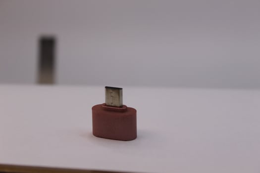 A small red usb plug sitting on top of a white surface photo