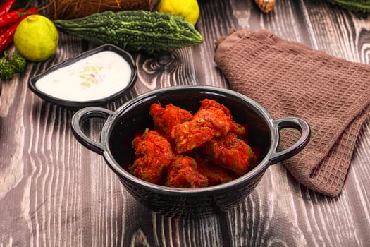A bowl of wings sitting on a table next to some vegetables photo