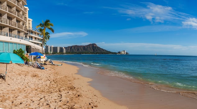 Golden sand beach with clear waters, colorful umbrellas, and Diamond Head crater in the background. A sailboat is visible on the horizon. photo