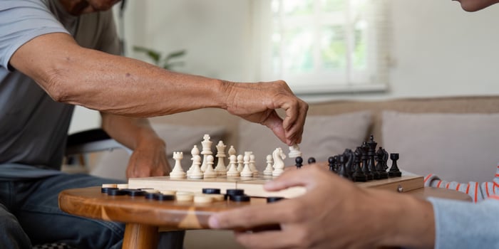 Close-up of father making a chess move while son focuses on the game. photo