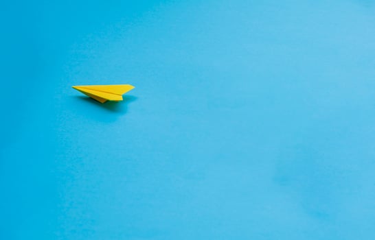 Yellow paper airplane on blue background photo