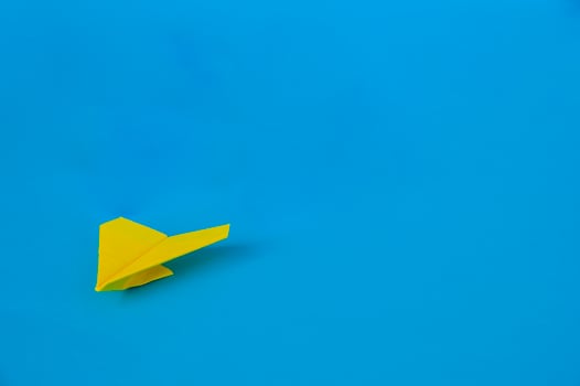 Side view of yellow paper airplane on blue background with customizable space for text. Business and Leadership skills concept photo
