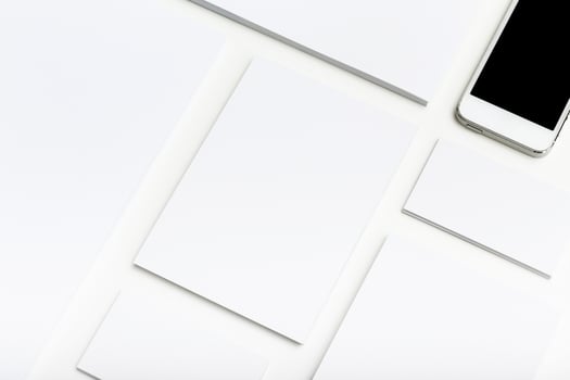 Minimalist workspace with blank papers and a smartphone on a clean white surface photo