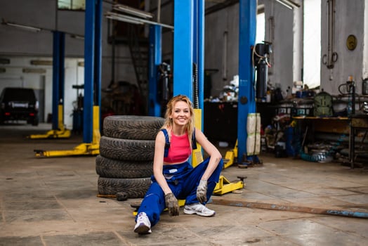 A woman sitting on a tire in a garage photo