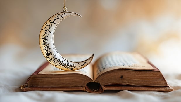 Delicate crescent moon ornament hangs over an open book with ornate pages in soft warm light photo