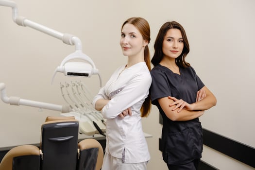 Smiling dentist and assistant with crossed hands looking at the camera in dental clinic photo