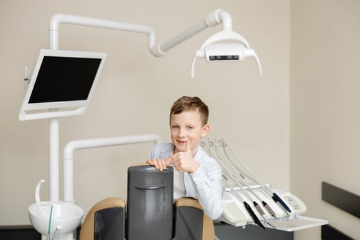 Boy looking at camera smiling while sitting in dentistry after teeth examination. photo