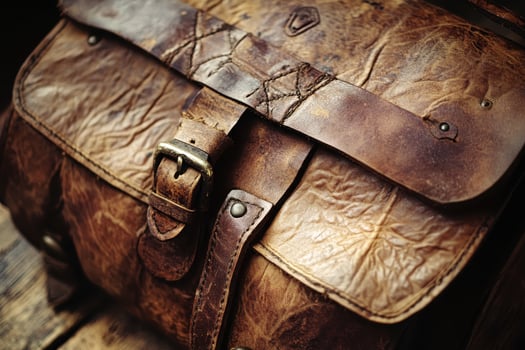 Aged brown leather messenger bag with buckle and strap photo