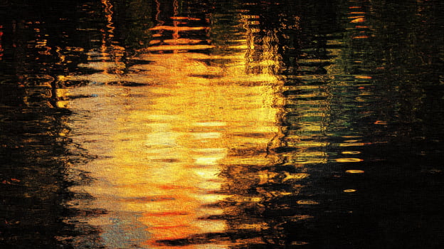 Reflective water surface displaying golden light and dark shadows photo