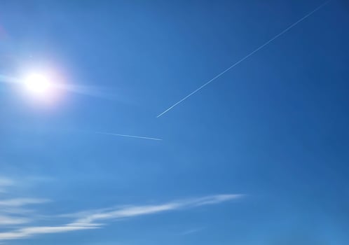 Blue sky, a glimmer of the sun, a trace of an airplane and clouds. photo