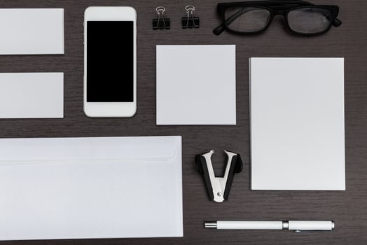 Workspace arrangement featuring blank stationery, smartphone, and office supplies for creative tasks photo