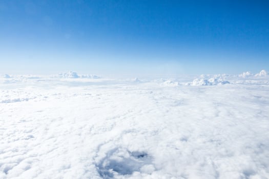Expansive view of cloud cover under a clear blue sky captured from above during a sunny afternoon photo