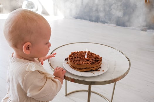 A baby sitting at a table with a cake with a candle photo