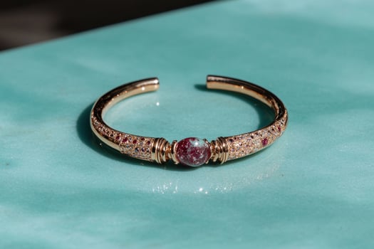 Elegant gold bracelet with a red gemstone on a blue surface photo