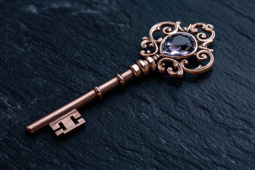 An ornate antique key with a purple gem on a textured dark background photo