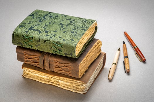 stack of retro journals with decked edge handmade paper pages and stylish pens, journaling concept photo