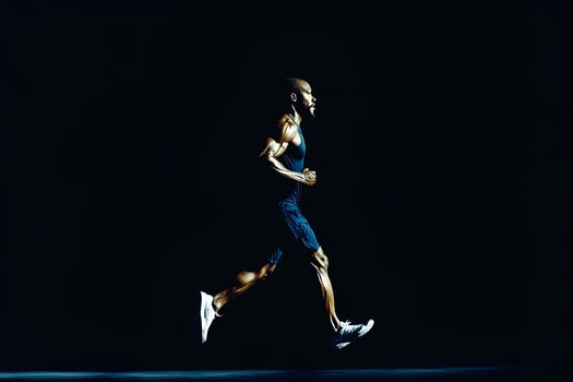 A dynamic full-length portrait of a man running, captured in motion against a solid black background. The image embodies energy, determination, and the power of sport and athleticism photo