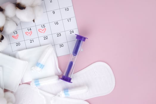 Women's menstrual pads, tampons, female menstruation calendar and alarm clock on a pink background. photo