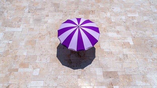 Purple and white striped beach umbrella on a stone patio photo