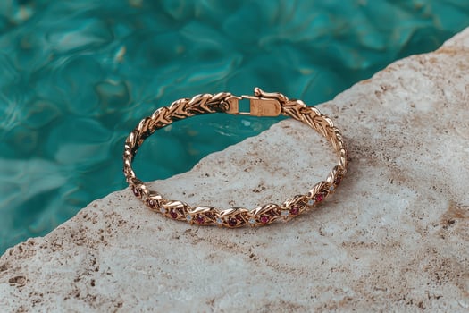Elegant gold bracelet with gemstones on a stone surface near water photo