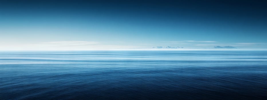 Expansive horizon meeting the tranquil depths of a serene blue ocean under a clear sky at dawn photo