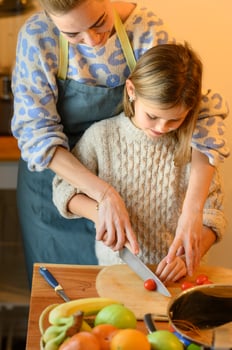 Mom gently pats her daughters head, appreciating her effort and teamwork in the kitchen. photo