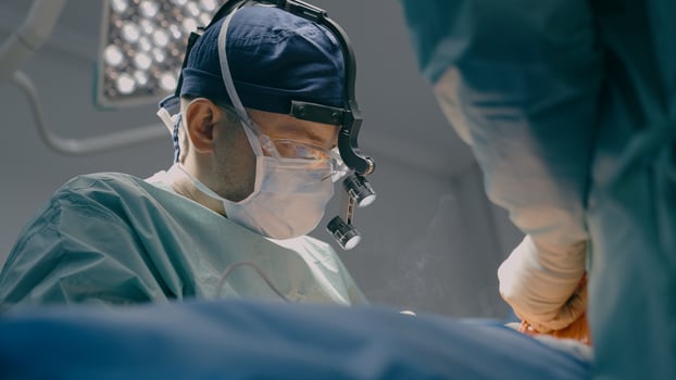 Close up surgeon man in protective mask physician doctor medic team operate patient laparoscopy surgical operation microscope surgery with medical tools in operating room hospital clinic health care photo