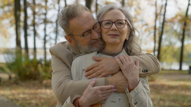 Retired mature old man hug woman from behind affectionate husband embrace wife cuddle romance tender relationship love Caucasian family couple male female bonding hugging in city autumn park outdoors photo