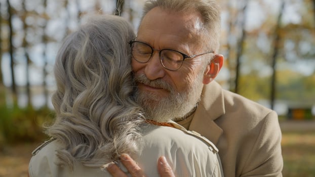 Mature couple hugging in autumn park senior gray-haired 60s aged man embracing woman happy married family embrace hug love support care romance at old age. Close up male face and female back outdoors photo