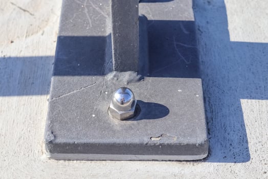 Shiny metal bolt securing railing to concrete surface photo
